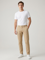 Men's slim-fit stretch chino trousers in khaki, worn by a model with a white tee and sneakers